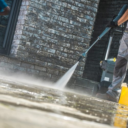 Men Washing Driveway Men Washing Driveway Using Pressure Washer. Spring Time Cleaning.